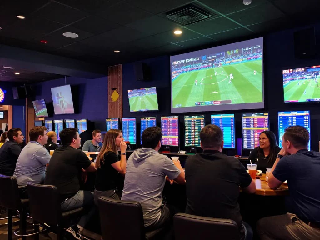 Sports betting event at bar showcasing ty-le-keo odds with excited patrons discussing strategies
